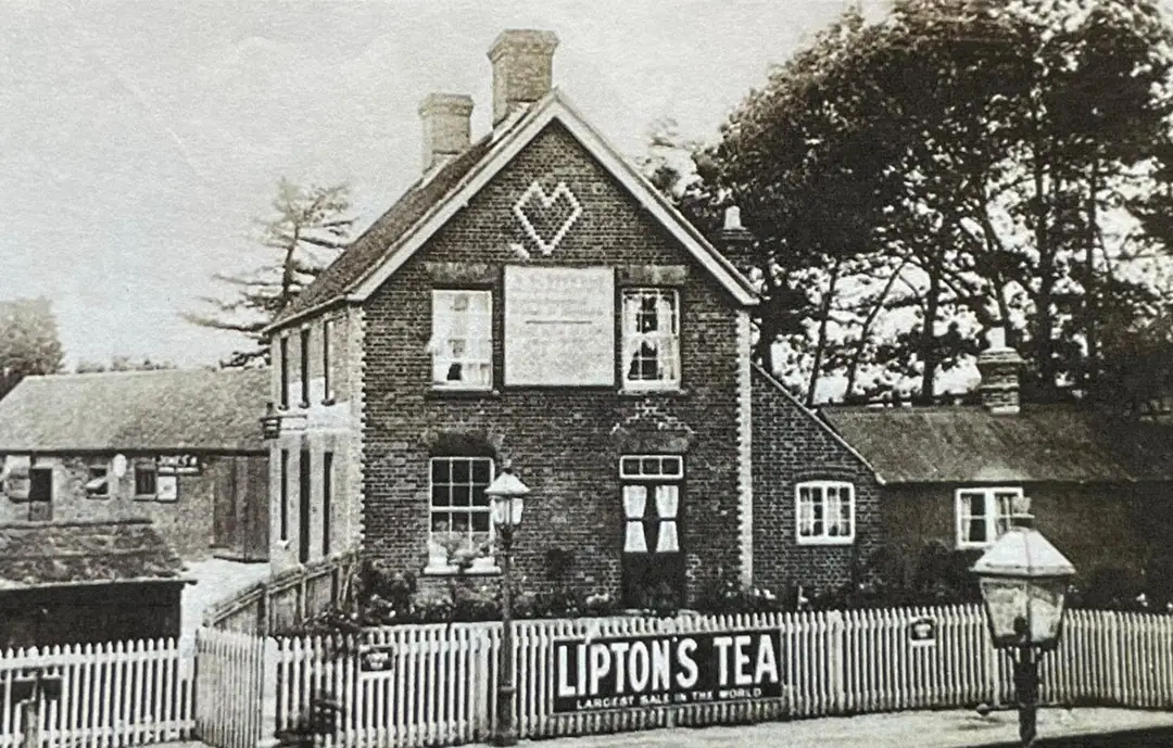 The Albion Hotel in the early 1900s, seen from the platform over a picket fence with a Lipton’s Tea sign