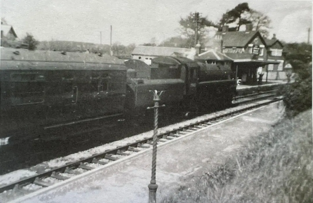 A steam engine and carriage beside the platform at Verwood station