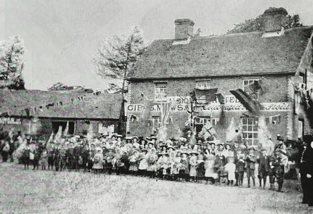 Schoolchildren in their best clothes and hats lined up outside the flag-hung Albion Hotel