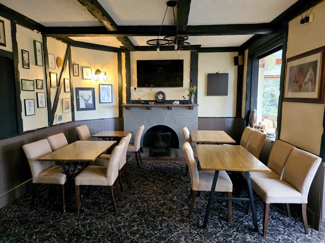 The beamed dining room with a grey brick fireplace, stag prints and wheel-shaped pendant lights