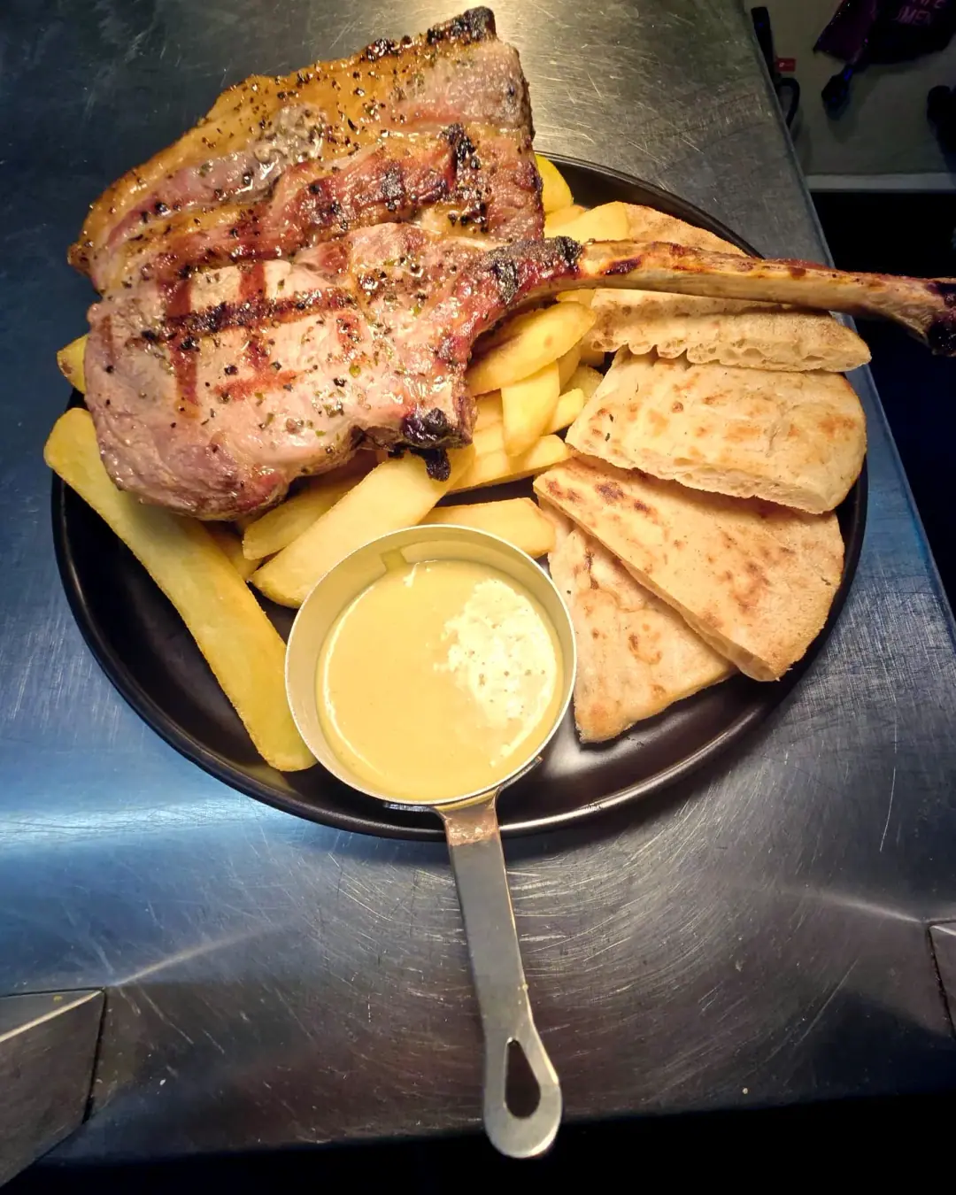 Grilled pork tomahawk with chips, pitta and sauce