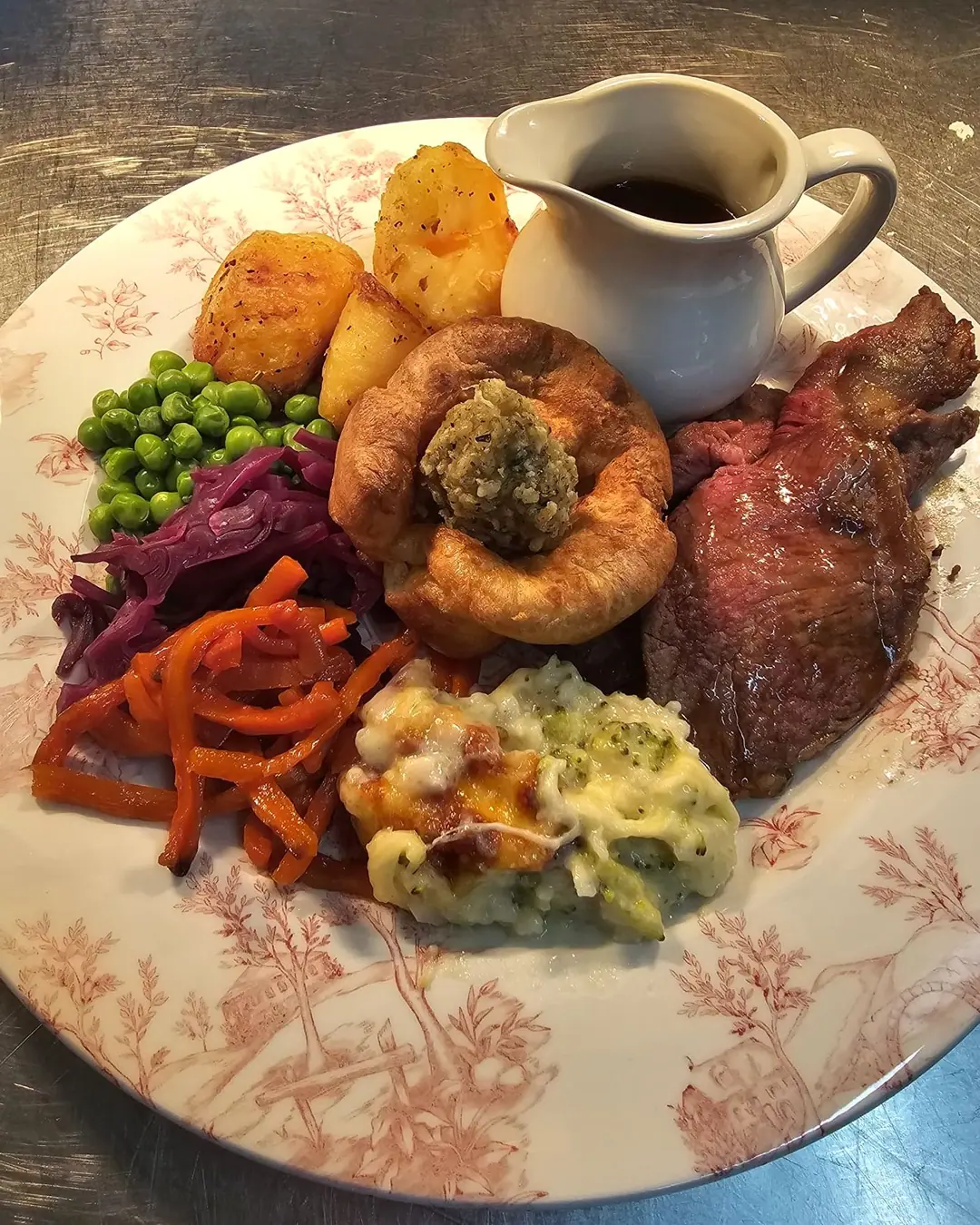 Roast beef with a Yorkshire pudding, roast potatoes, cauliflower cheese, vegetables and a jug of gravy