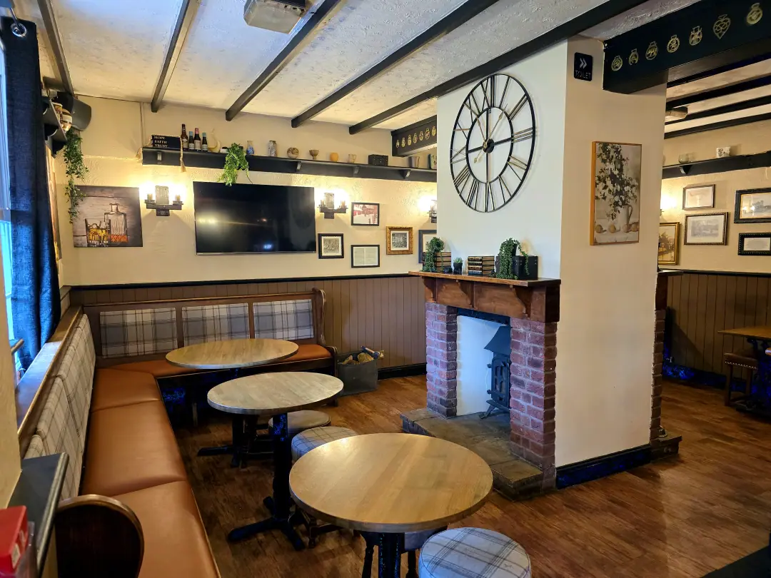 The snug: a leather banquette, tartan stools and a brick fireplace beneath a large skeleton clock